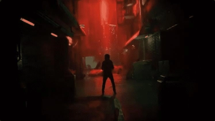 A shrouded figure in a dark city alley with a red light shining in the distance