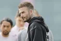 Soccer legend, David Beckham, walks across the field in a black sweatshirt