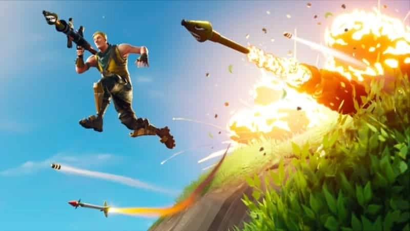 Мужчина-персонаж Fortnite прыгает через холм с РПГ и кучей ракет, стреляющих из-за него