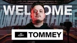 Call of Duty Warzone player and streamer Thomas “Tommey” Trewren stands confidently in front of his gamertag and the 100 Thieves logo with the word Welcome behind him