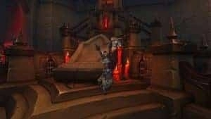 Персонаж World of Warcraft в мантии взволнованно поднимает руки перед большим алтарем с горящими красными свечами.