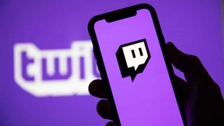 Логотип Twitch появляется на фиолетовом фоне на экране смартфона.