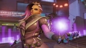 balance Overwatch hero Sombra holds a purple sphere of energy.