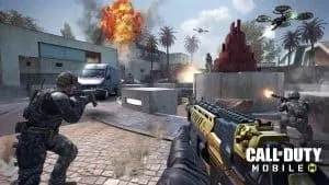 Two operators approach a flaming building with their weapons drawn.The Call of Duty Mobile logo appears in the bottom right corner of the frame