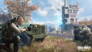 An operator checks their map while taking cover behind a vehicle as their allies move toward a target on the outskirts of a mountainside town in promotional art for Call of Duty: Mobile