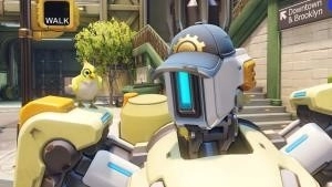 The Overwatch Hero Bastion, an AI robot, stands on a sunny Brooklyn street in a baseball cap