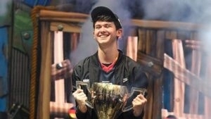 Pro Fortnite player Kyle “Bugha” Giersdorf holds a trophy and smiles after his victory at the Fortnite World Cup.