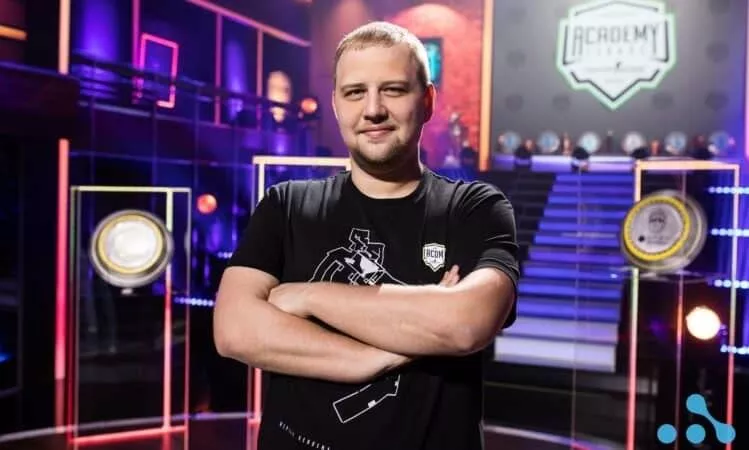 Евгений Шепелев, ведущий киберспортивный менеджер WePlay Esports, стоит с руками и улыбкой на лице в студии Академии Лиги.