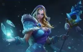 The Dota 2 Hero Crystal Maiden stands in her blue and white fur robes clutching her staff in one hand, in he palm of the other she summons a trio of shimmering blue icicles